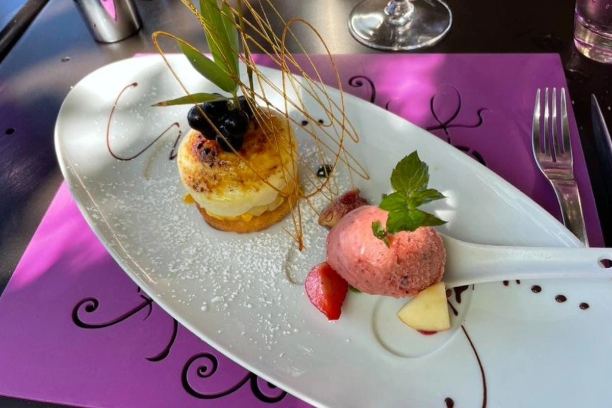 Delicate dessert plating with a pink ice cream scoop, fruit, and chocolate on a white plate.