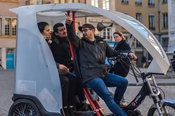 A group of people in Lyon enjoying a ride on a pedal taxi.